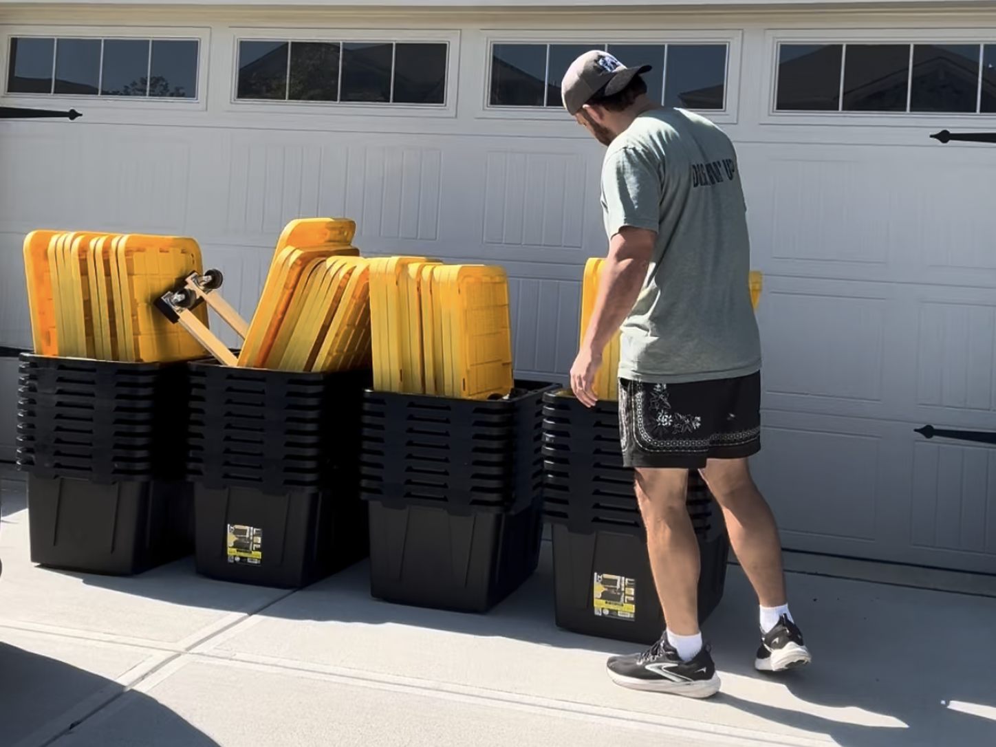 Empty moving totes and lids stacked in a driveway ready for pickup