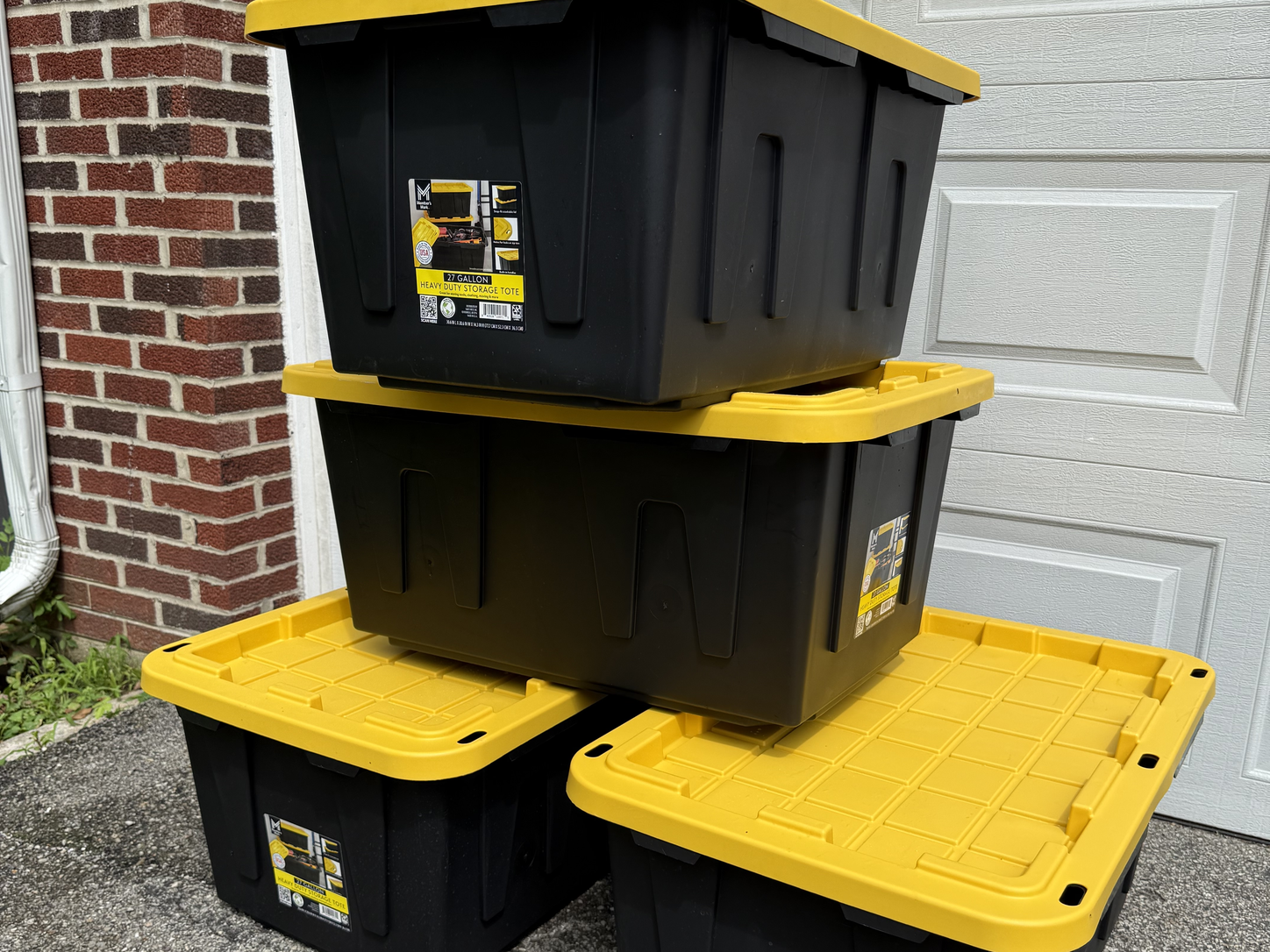 Stacked black and yellow reusable moving totes with attached lids